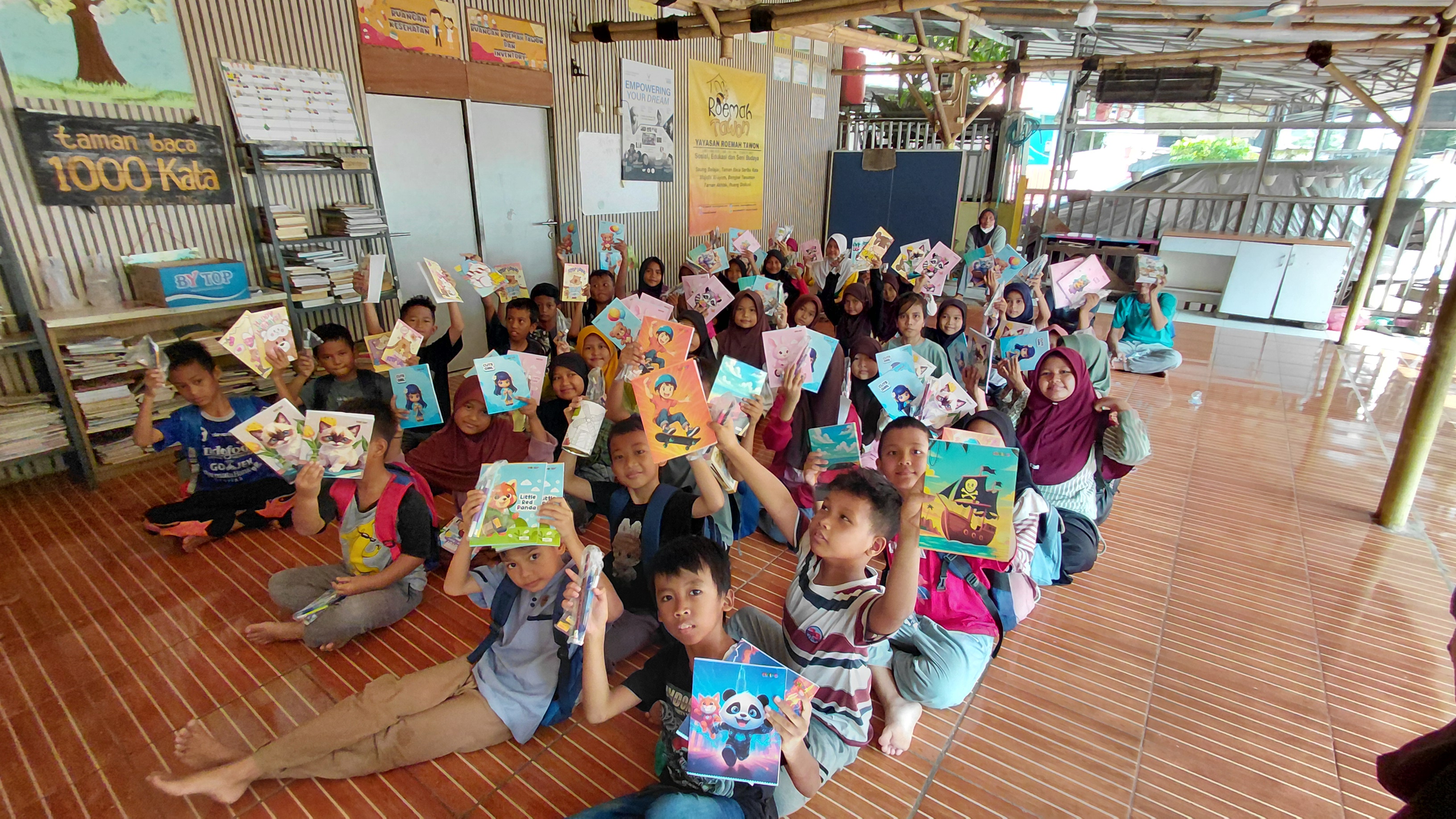 Anak-anak Roemah Tawon menunjukkan buku dalam kegiatan bersama BEM FKIP UNIS